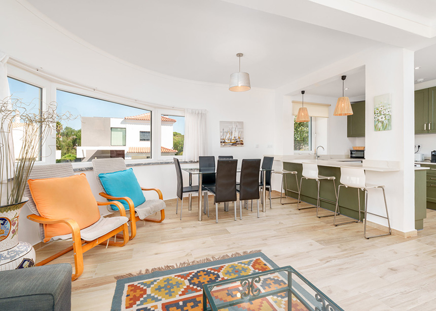 Interior de cocina abierta al salón con isla en tonos verde oliva