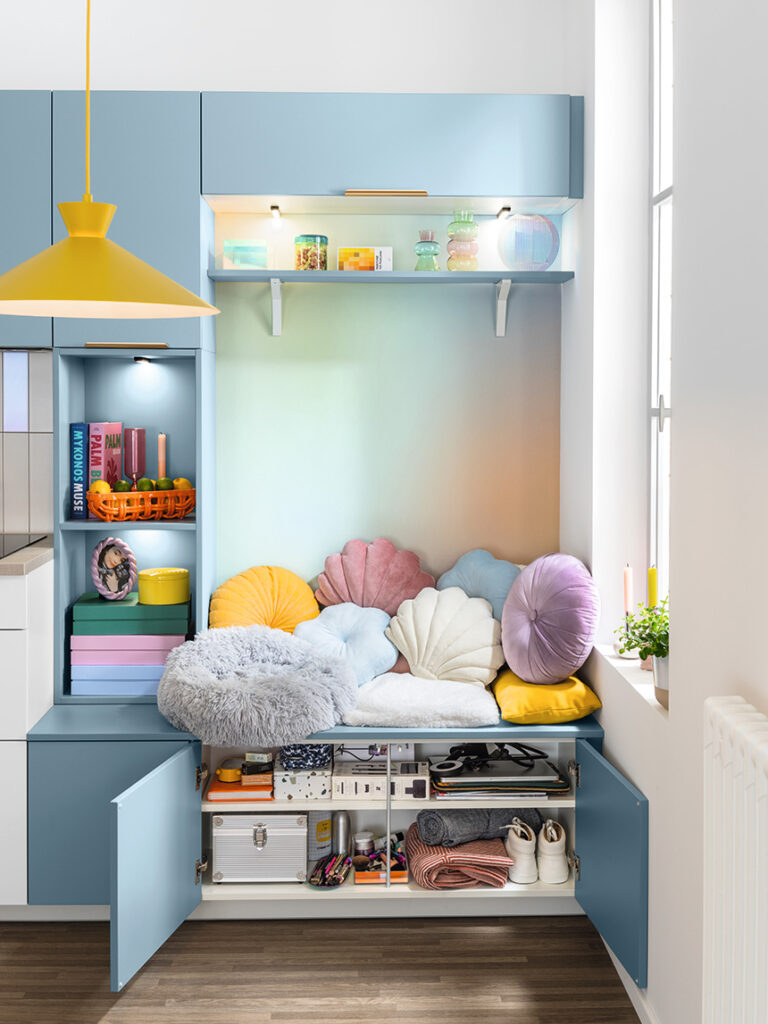 Cocina Rainbow de SoCoo’c con muebles azules, banco junto a la ventana y zona familiar.
